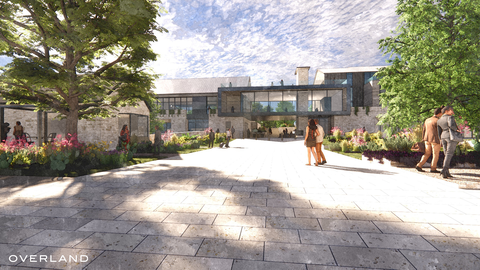 Modern building with extensive use of glass, surrounded by greenery in Fredericksburg, Texas. Several people walk along a wide, paved pathway under a partly cloudy sky. Text "OVERLAND" is visible in the bottom left corner, hinting at Overland Partners' involvement in this luxury resort design.