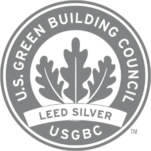 A circular logo of the U.S. Green Building Council featuring the text "LEED Silver" and "USGBC" with a leaf design in the center, proudly displayed by Austin Community College's Rio Grande campus.