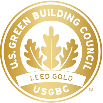 A gold circular badge with the text "U.S. Green Building Council, LEED Gold, USGBC" surrounding a stylized leaf design, often seen at eco-conscious facilities such as a Homeless Recovery Center.