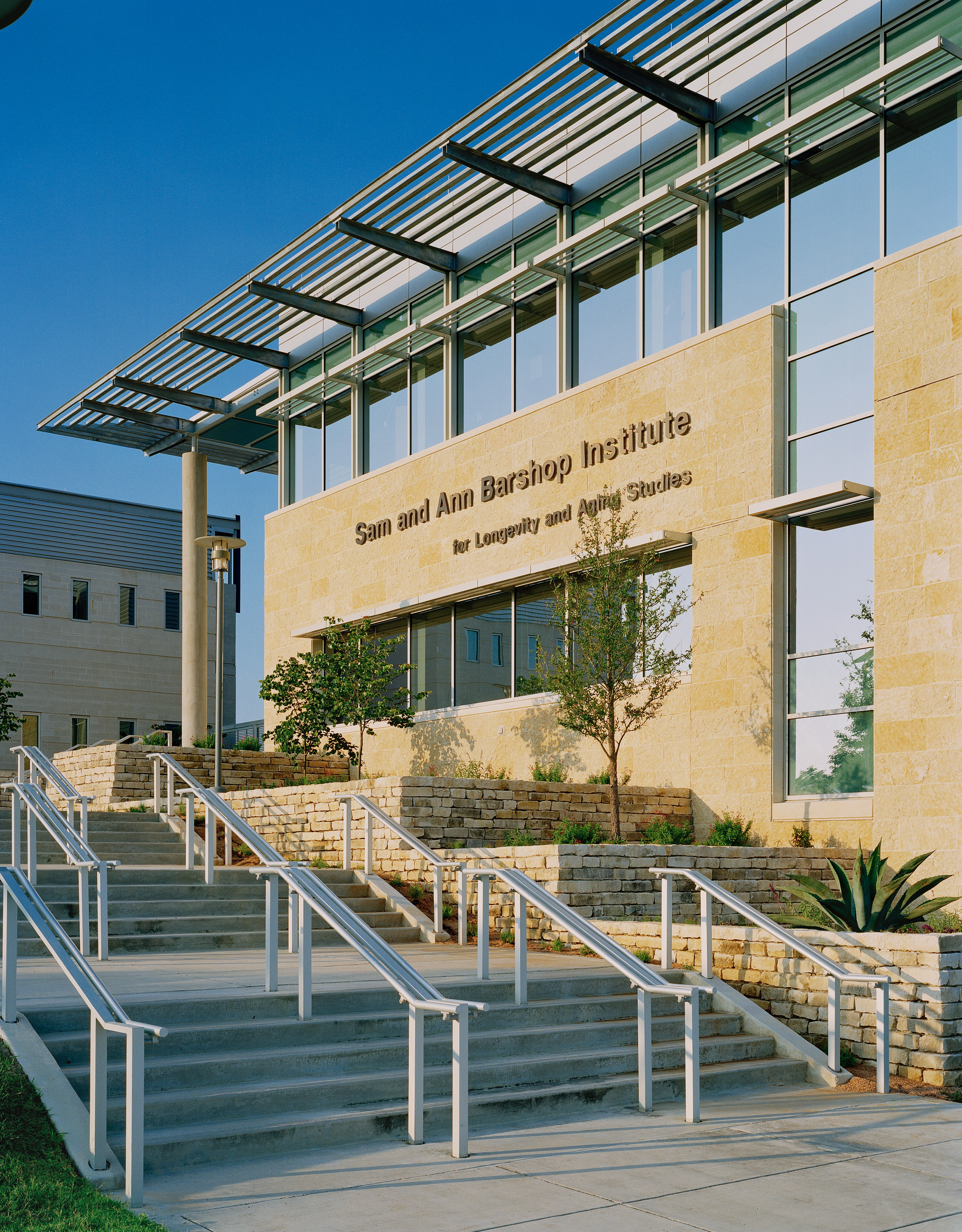 The image shows the Sam and Ann Barshop Institute for Longevity and Aging Studies building with a modern architectural design, featuring Auto Draft elements like sleek stairs and innovative landscaping.