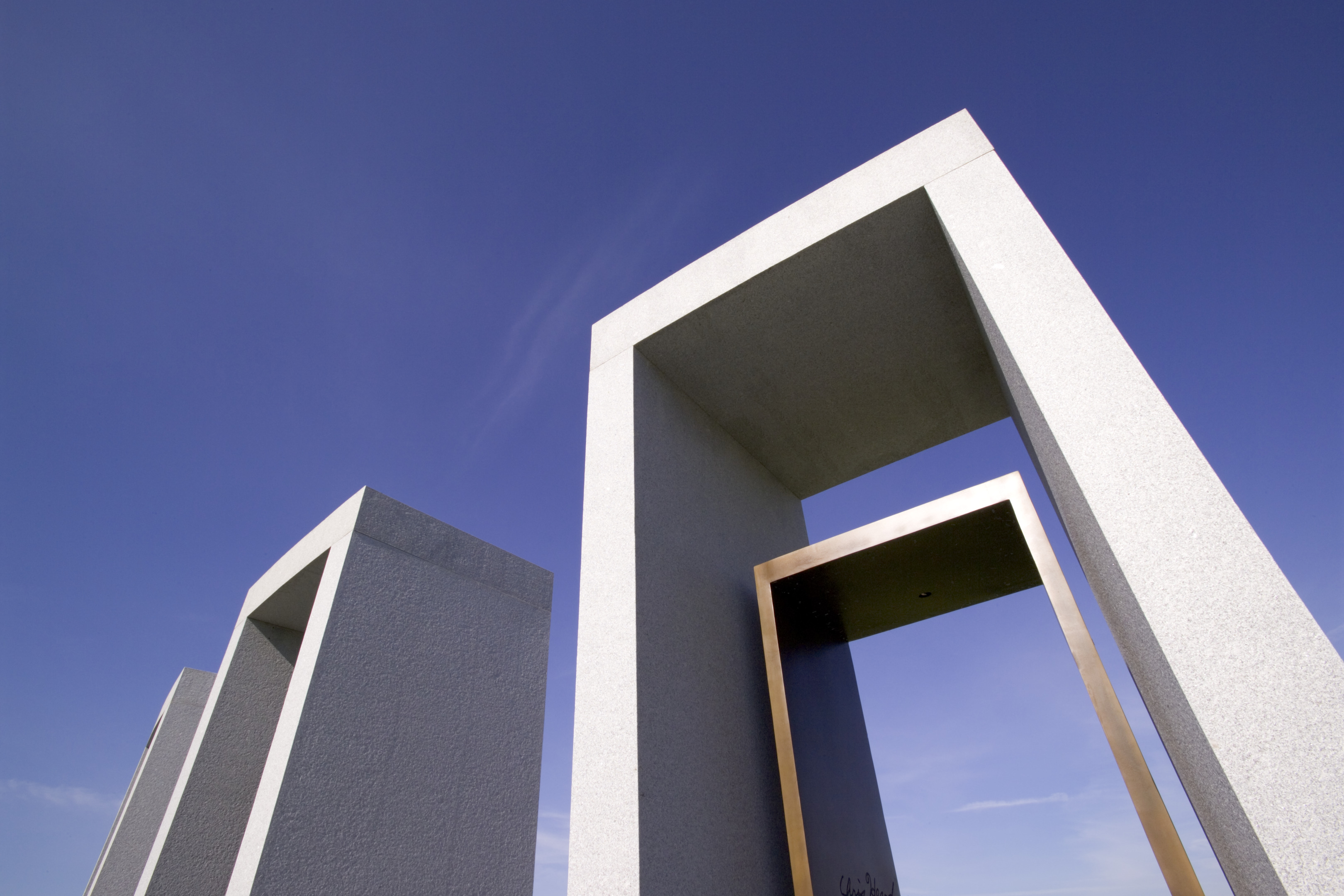 Tall stone structures with rectangular openings stand against a clear blue sky, viewed from a low angle.