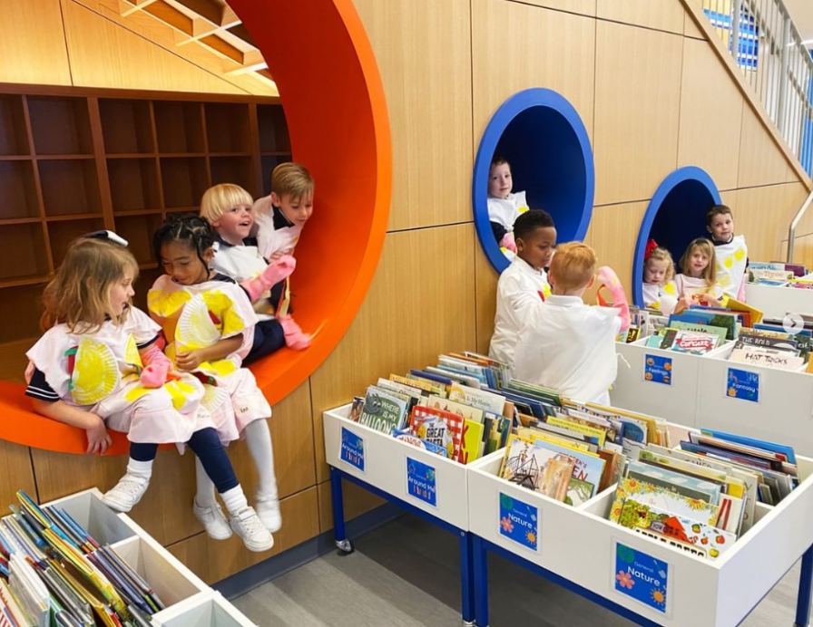 Children sitting in colorful circular nooks above bins of assorted books in a library, creating an environment where the joy of reading makes a lasting impact.