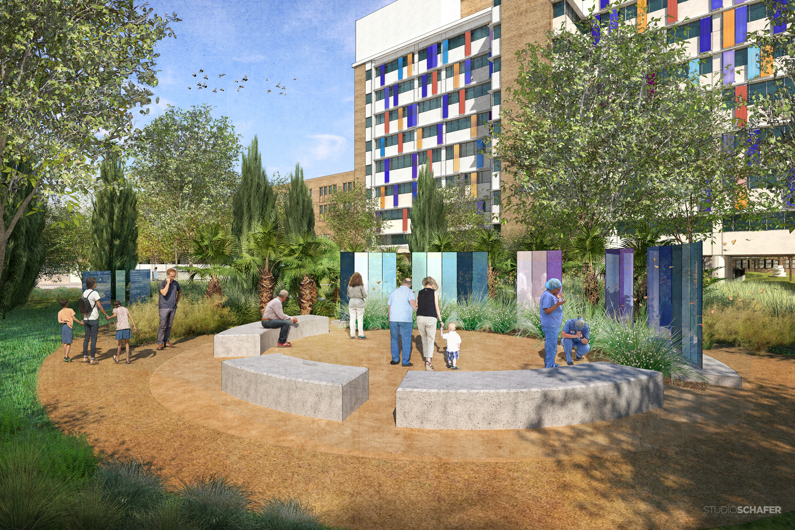 People are gathered in a circular outdoor area with benches and tall, abstract panels, surrounded by trees and greenery, in front of Christus Children's Hospital in San Antonio. The biophilic garden design enhances the vibrant atmosphere created by the colorful window facades of the multi-story building.