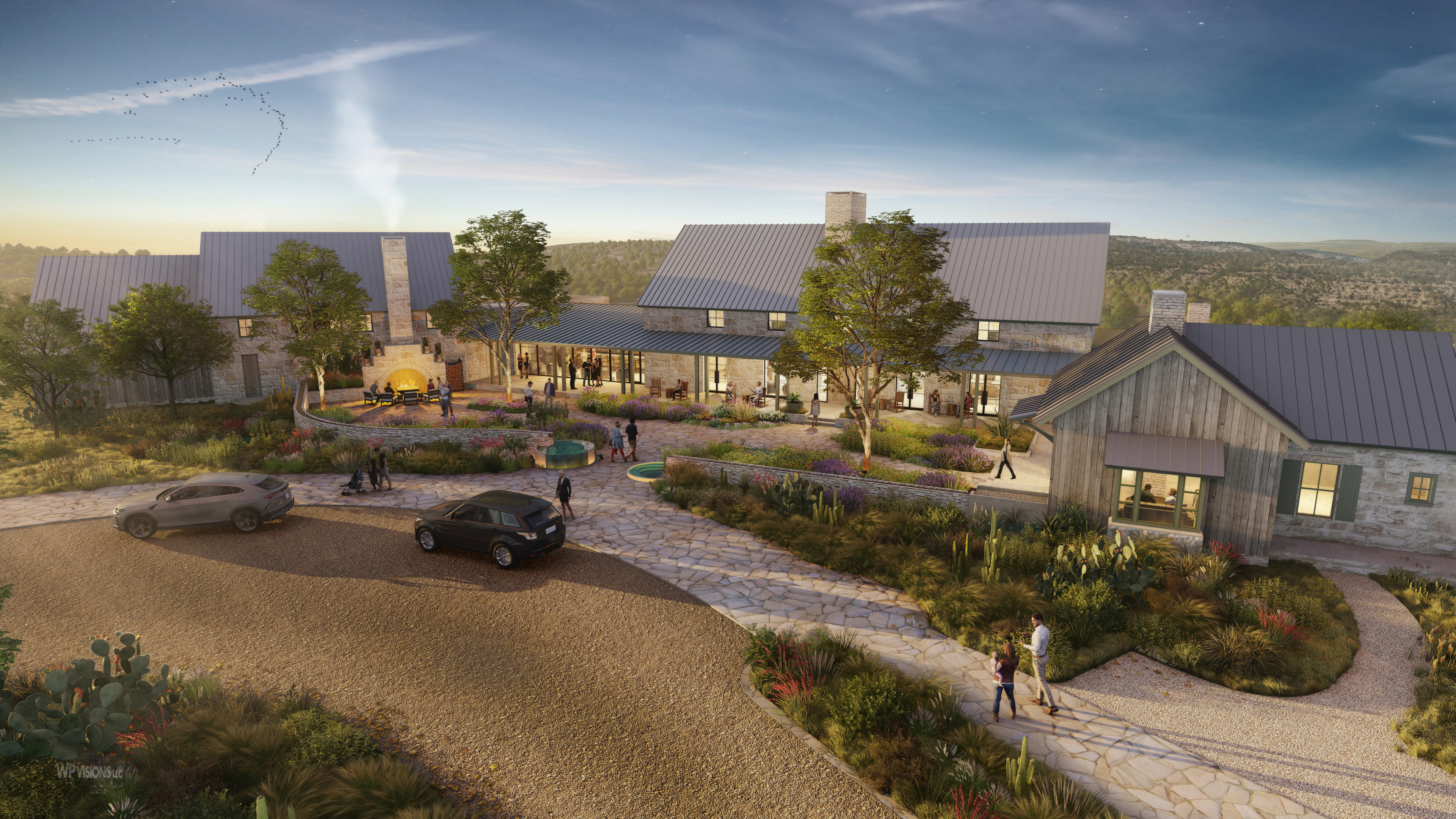 A scenic view of The Inn at Mirasol Springs, Auberge Resorts Collection, showcases a modern rustic building complex surrounded by trees and greenery under a twilight sky. Several people walk around while cars are parked near a stone pathway.