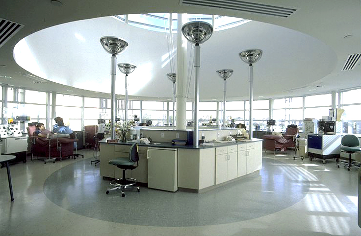 A modern, circular hospital room in South Texas with multiple patient chairs, medical equipment, and a central nurses' station. Patients are seated while undergoing treatments at the Tissue Center.