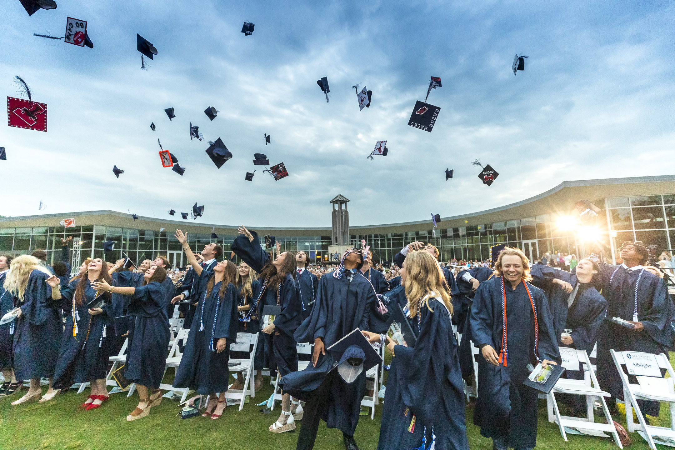 Graduates in caps and gowns celebrate by joyfully tossing their caps into the air outside a sleek, modern building, capturing a moment of triumph and new beginnings.